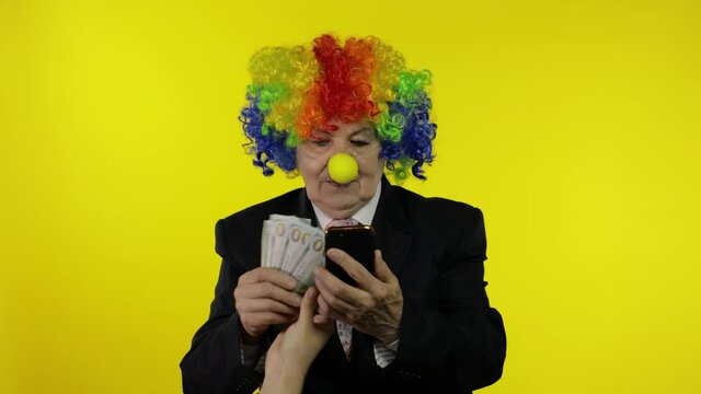 Senior clown businesswoman entrepreneur loses money on online smartphone working