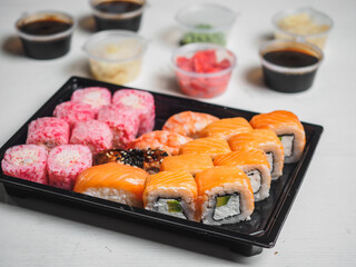 Set of sushi rolls in delivery plastic boxes on white background