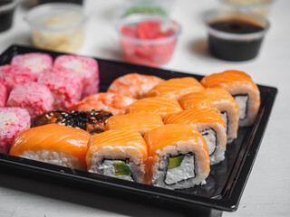 Set of sushi rolls in delivery plastic boxes on white background