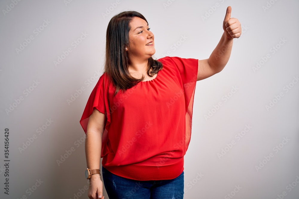 Wall mural beautiful brunette plus size woman wearing casual red t-shirt over isolated white background looking