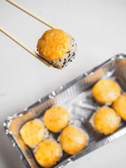 Hot cheese rolls in foil container with wooden chopsticks