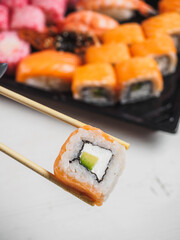 Roll with salmon, avocado and cheese in wooden chopsticks