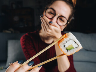 Bad negative emotions of woman with salmon roll in chopsticks