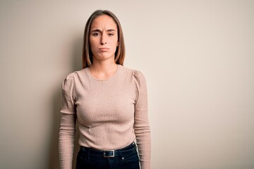 Young beautiful woman wearing casual sweater standing over isolated white background skeptic and...