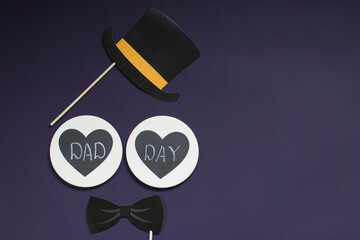 Happy father's day. On a violet background is a bow tie, a bowler hat, two hearts with the...