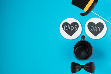 Happy father's day. On a blue background - a bow tie, a bowler hat, a tea mug, two hearts with the inscription dad's day.