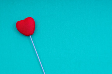 Red heart on a stick, on a pink background. Conceptual and creative photography. Copy space.