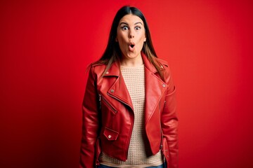 Young beautiful woman wearing red leather jacket over isolated background afraid and shocked with surprise expression, fear and excited face.