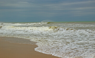 View of the sandy beach and sea during a storm at dusk