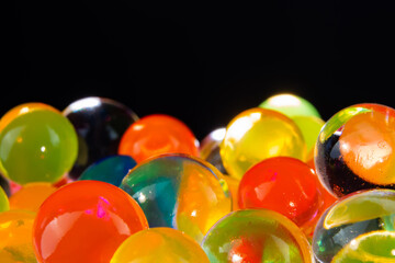 multi-colored silicone gel balls in a glass on a black background