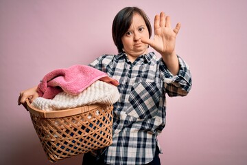 Young down syndrome woman doing housework domestic chores holding laundry wicker basket with open...