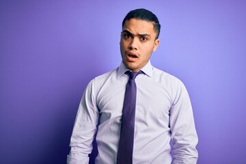 Young brazilian businessman wearing elegant tie standing over isolated purple background In shock face, looking skeptical and sarcastic, surprised with open mouth