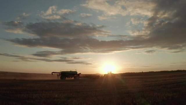 A Tractor Seeder At Work In The Farm During Sunrise In Swift Current, Saskatchewan, Canada - wide drone shot