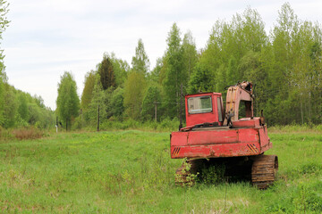 abandoned red excavator in the forest near the road