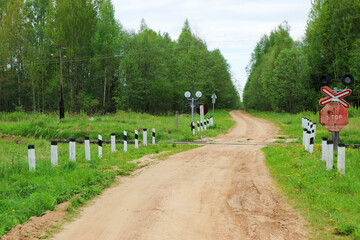 Naklejka premium railway crossing with abandoned railway on a dirt road in the forest