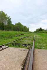 Obraz premium view from railroad crossing to abandoned rail track overgrown with grass in Russia