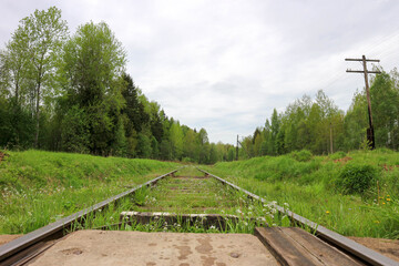 view from railroad crossing to abandoned rail track overgrown with grass in Russia