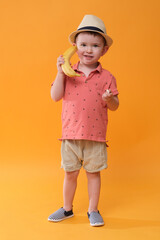 Baby boy as a fruit lover. Holiday style. Studio shoot on orange background.