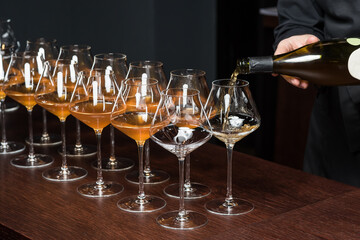The waiter pours white wine into the glasses