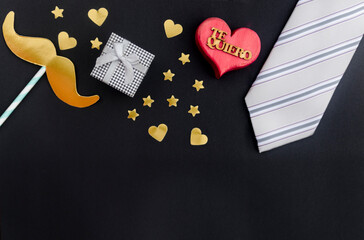 Concepto del día del padre - regalo, bigote, corazón y corbata sobre fondo negro

