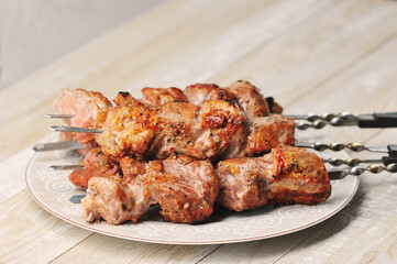 pork skewers on skewers in a plate on a wooden background