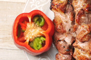 red pepper and pork skewers on skewers in a plate on a wooden background