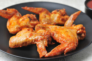 fried marinated chicken wings on a black plate
