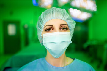 Female medical doctor with brown eyes in surgical mask looking at you