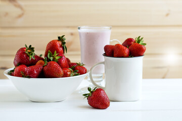 Red ripe strawberries in a white plate on a white wooden table. Fresh berries, healthy food, detox for the body, vegetarian.