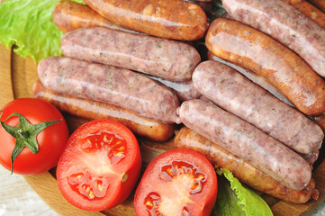 raw grilled sausages on a wooden round Board with tomatoes