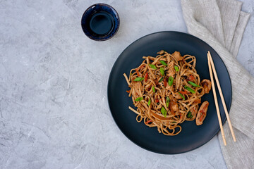 Asian udon noodles with chicken vegetables and teriyaki sauce with chopsticks and a linen napkin on...