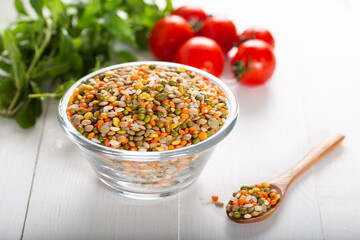 Colorful various beans or lentils and whole grains seeds or cereal in bowl with fresh vegetables on wooden background.