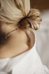 The view from behind the neck and shoulders of a beautiful young blonde with hair tied in a bundle. Youth, lifestyle and happiness concept. Studio shooting, soft focus.