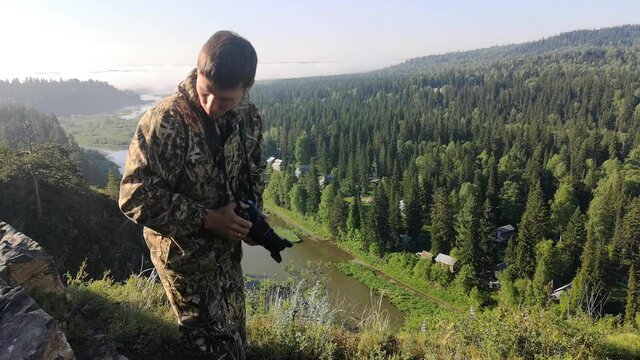 a man photographs the morning landscape. Standing on top of a mountain in front of a beautiful view