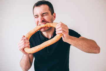 Young man isolated over background. Guybiting piece of round bun with pleasure. Fresh tasty delicious bread. Yummy food.