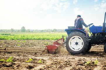 Farmer on a tractor cultivates a farm field. Soil milling, crumbling and mixing. Grinding and...