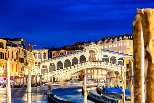 Rialto bridge and Grand Canal at twilight blue hour in Venice, Italy. Gondolas on the foreground. Tourism and travel concept. © Nikolay N. Antonov