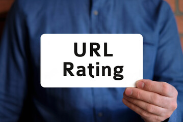 Url rating text on a white sign in the hand of a man in a blue shirt