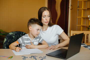 A mother and her child are engaged in distance learning at home in front of the computer. Stay at home, training