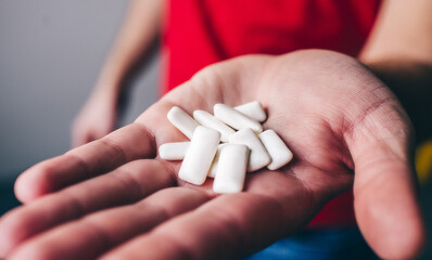Man's hand holding mint chewing gum on hand and show it on camera. Close up. White tablets.