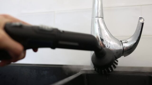 cleaning the sink and faucet with a steam cleaner, disinfection in the house.