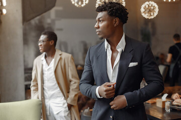 Black men in a cafe. Guy talking. Man in a black suit. - Powered by Adobe