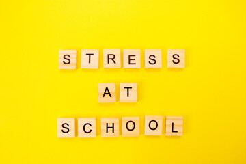 Words stress at school. Wooden blocks with an inscription on top on a yellow background. Social problems of teenagers and children