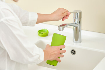 Woman dish washing a thermos bottle. Running water