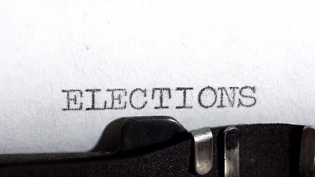 Typing ELECTIONS in black ink on an old vintage typewriter. In the context of US elections in 2020. Close up selective focus.