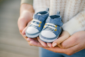 Closeup of a hands holding a pair of small blue baby shoes - Powered by Adobe