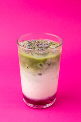 Sweet iced latte with green matcha and strawberry syrup , top view on bright magenta background