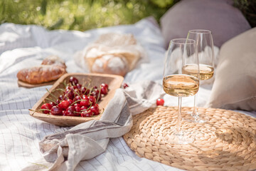 Aesthetic picnic outdoors with wine glasses bread berries and flowers. Rustic picnic with neutral...