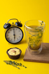 Buckwheat tea and vegan no flour lemon tart on minimalist bright yellow background with black clock and wooden board