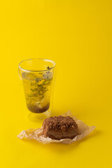 A tall glass of buckwheat tea and medovik cake on bright yellow studio background